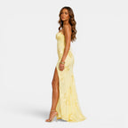 Woman wearing a yellow lace dress with a slit on a white background
