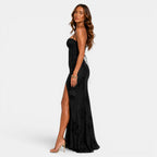 Woman wearing a black strapless gown with a high slit on a white background