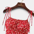 Red floral dress with tied straps on a wooden hanger with 'Belcien' branding.