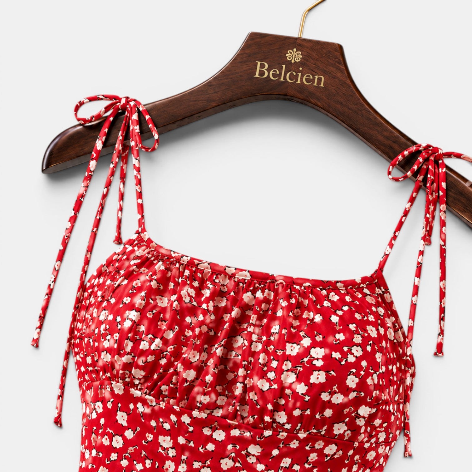 Red floral dress with tied straps on a wooden hanger with 'Belcien' branding.