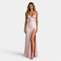 Woman wearing a pink satin gown with a high slit on a white background