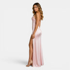 Woman wearing a pink satin dress with a high slit on a white background