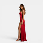 Woman wearing a red satin dress with a high slit on a white background
