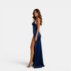 Woman wearing a blue satin gown with a high slit on a white background