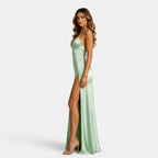 Woman wearing a light green satin dress with a high slit on a white background