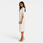 Woman wearing a white dress with cut-out shoulders on a white background