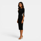 Woman wearing a black dress with gold accents on a white background