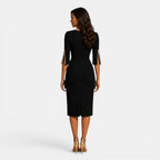 Woman wearing a black dress with gold accents on a white background