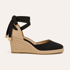 A single women's wedge espadrille sandal in black suede and natural jute, featuring a black fabric ankle strap with a bow, shown against a light cream background.