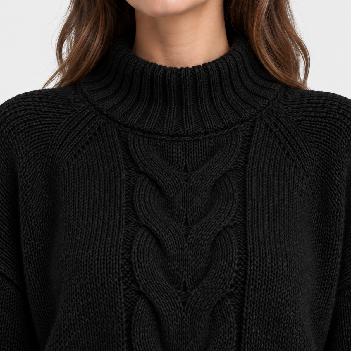 Close-up of a person wearing a black cable-knit mock neck sweater, showing the detailed knit texture and the lower edge of the hair against a plain light background.