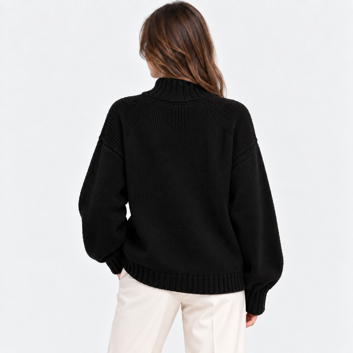A woman shown from the back wearing a black ribbed knit mock-neck sweater and cream-colored pants, set against a plain white studio background.