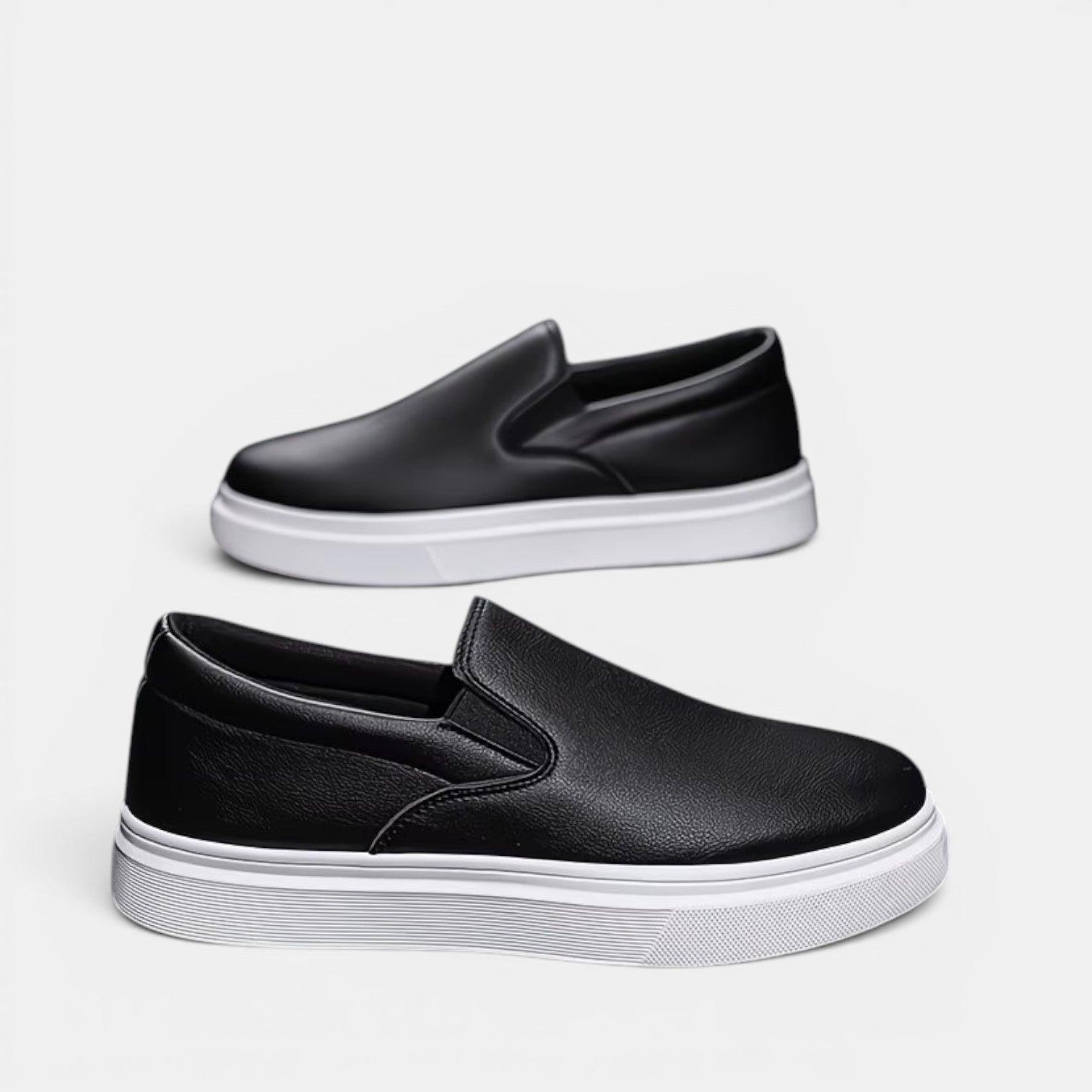 Black slip-on shoes with white soles on a light gray background