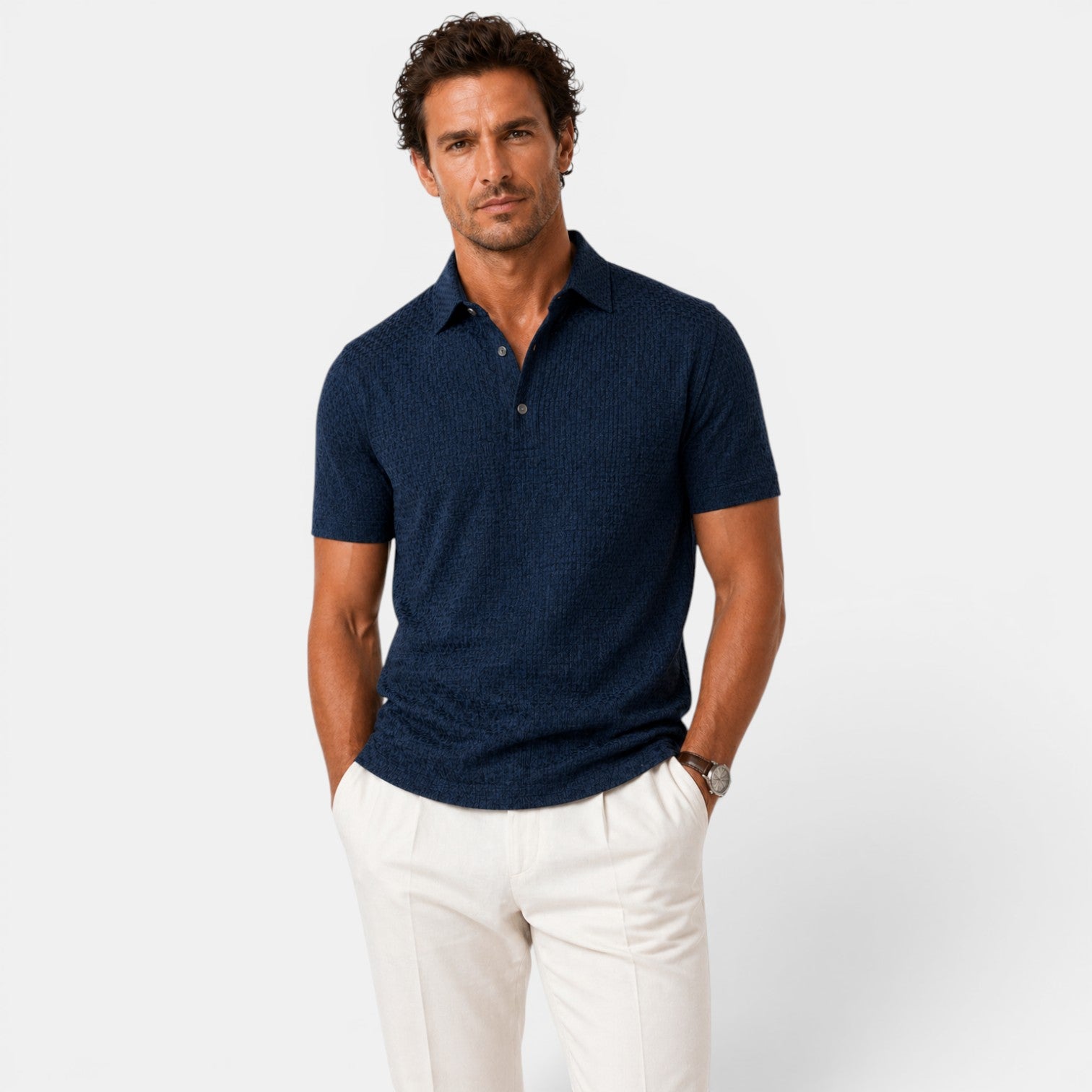 Man wearing a navy polo shirt and white pants on a light gray background