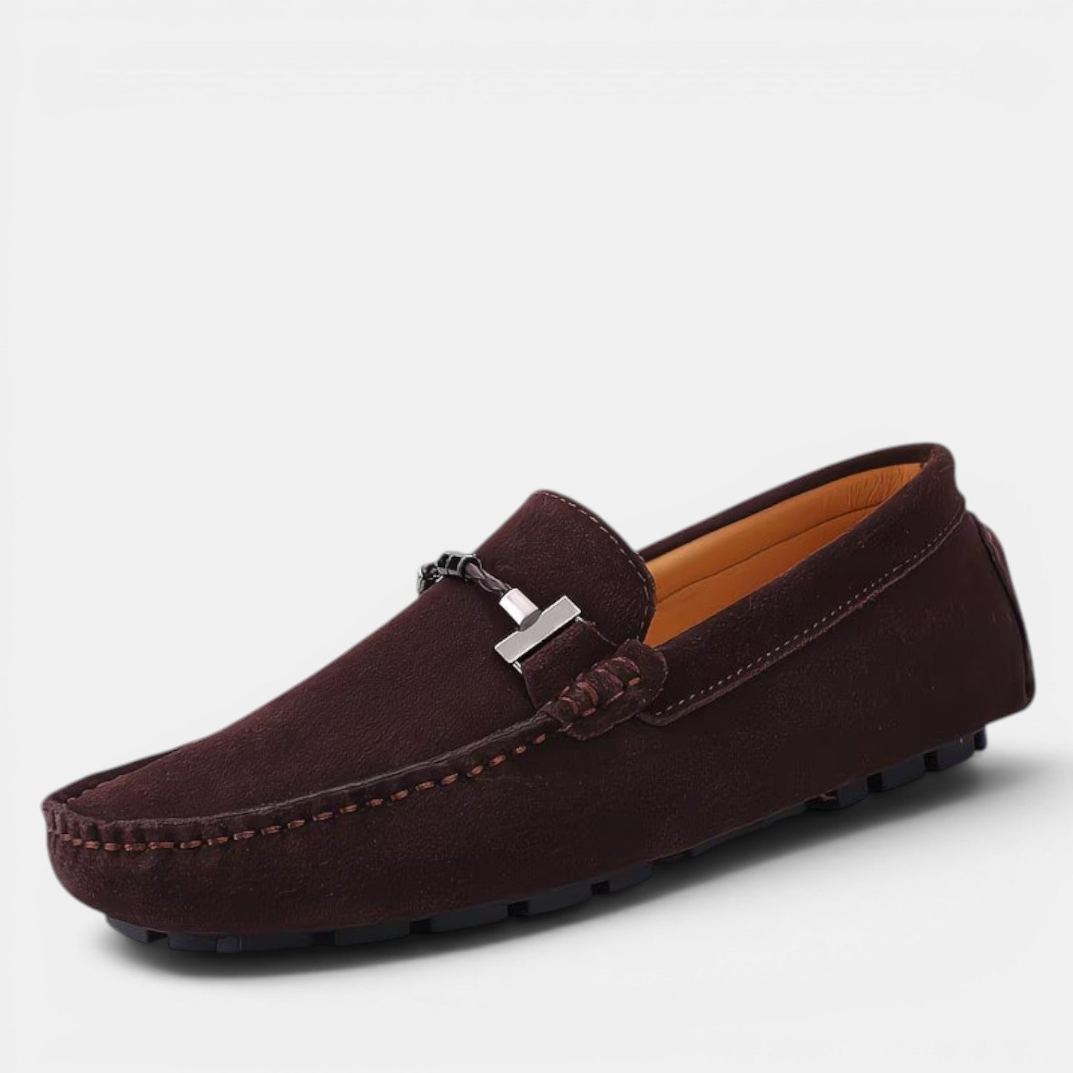 Brown loafer shoe with a silver buckle on a light gray background