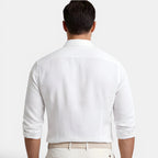 Man wearing a white dress shirt and beige pants on a light gray background