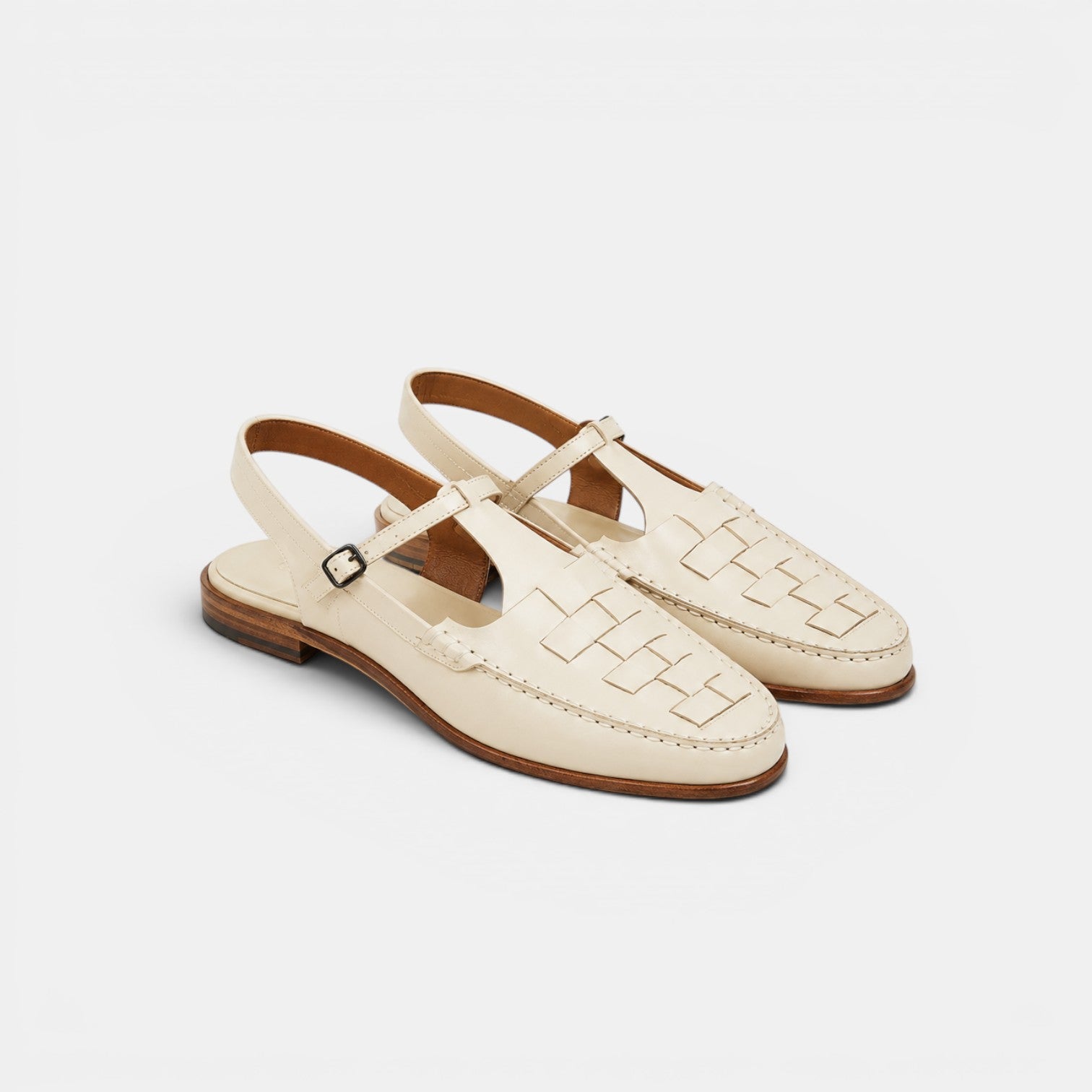 Pair of cream-colored sandals with a woven pattern on a light gray background