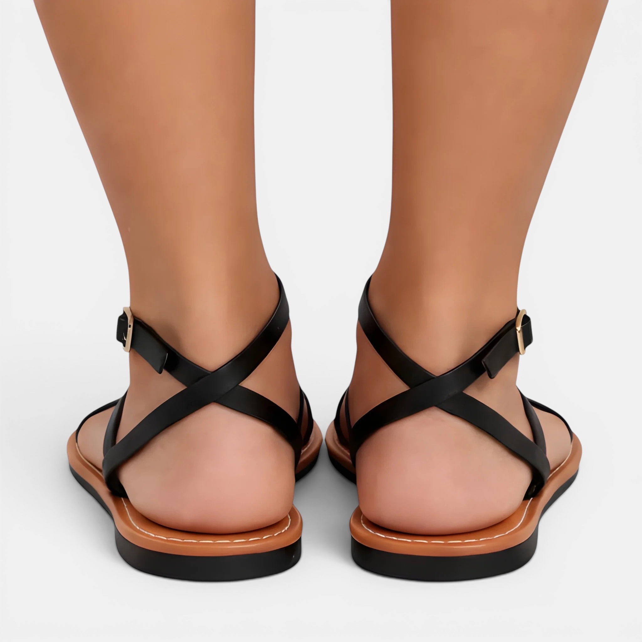 Black strappy sandals on feet with a plain background