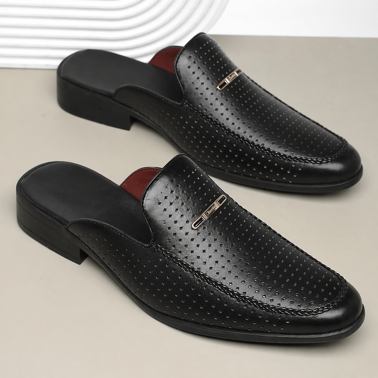Black perforated loafers on a light gray background