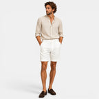 Man wearing a beige shirt and white shorts on a white background