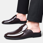 Brown loafers worn with black pants on a light gray background