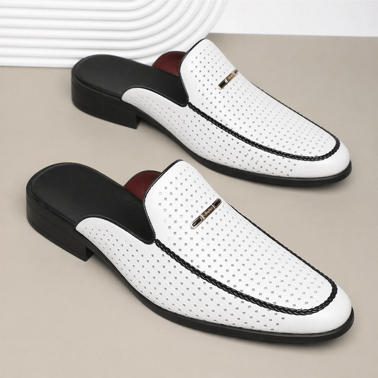 White leather slip-on shoes with black accents on a beige surface