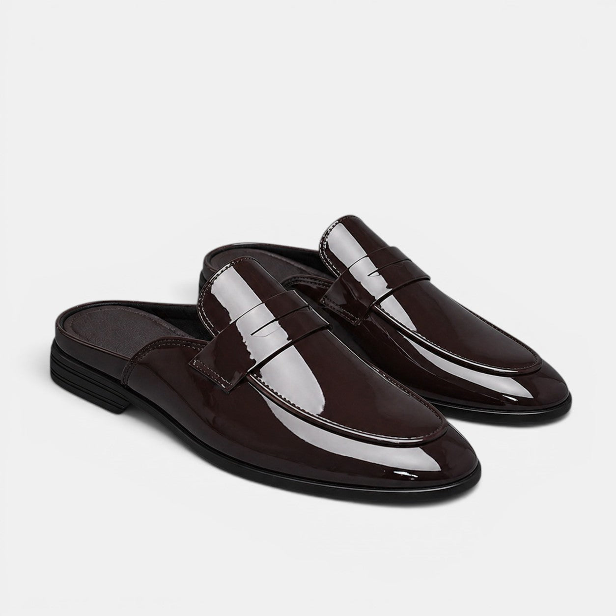 Pair of brown patent leather loafers on a light gray background