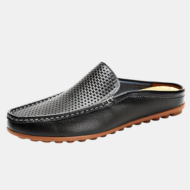 Black slip-on shoe with brown sole on a light gray background