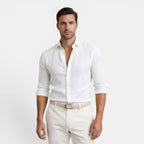 Man wearing a white dress shirt and white pants on a light gray background
