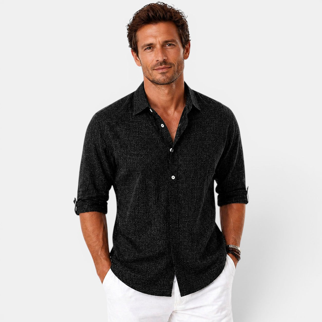 Man wearing a black textured shirt and white pants on a light gray background