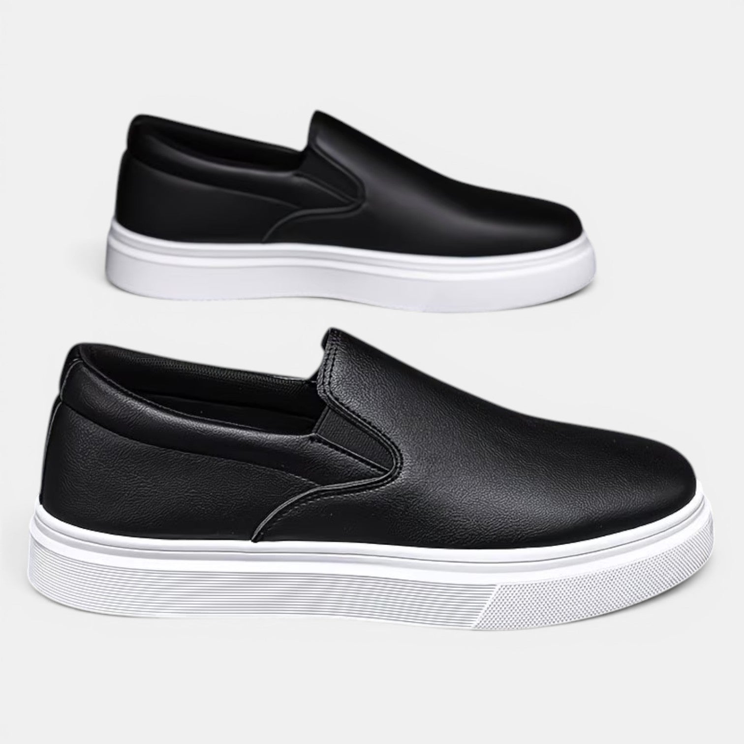 Two black slip-on shoes with white soles on a light gray background