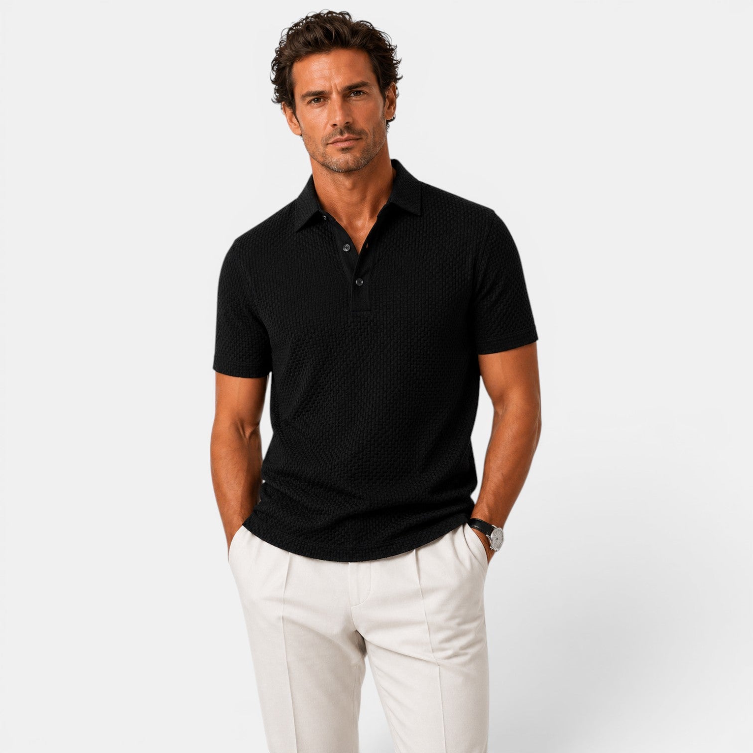Man wearing a black polo shirt and white pants on a light gray background
