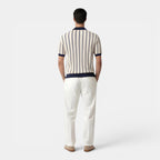 Man wearing a striped shirt and white pants on a white background