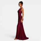Woman wearing a burgundy one-shoulder gown on a white background