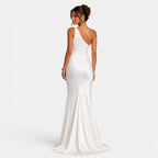 Woman wearing a white one-shoulder gown on a light gray background