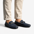 Navy loafers worn with beige pants on a white background