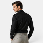Man wearing a black dress shirt and light gray pants on a white background