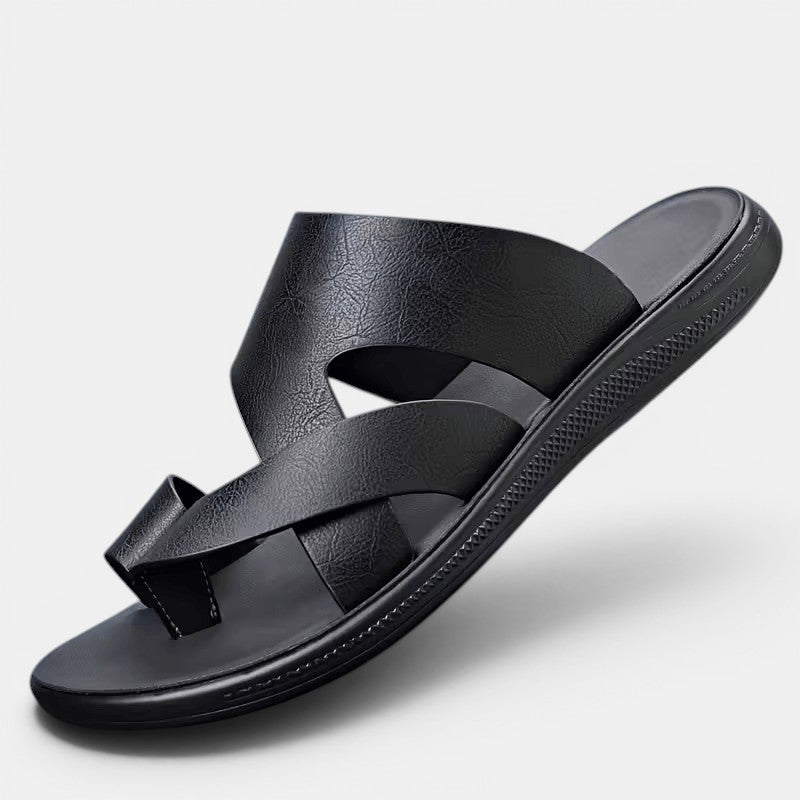 Black sandal with criss-cross straps on a light gray background