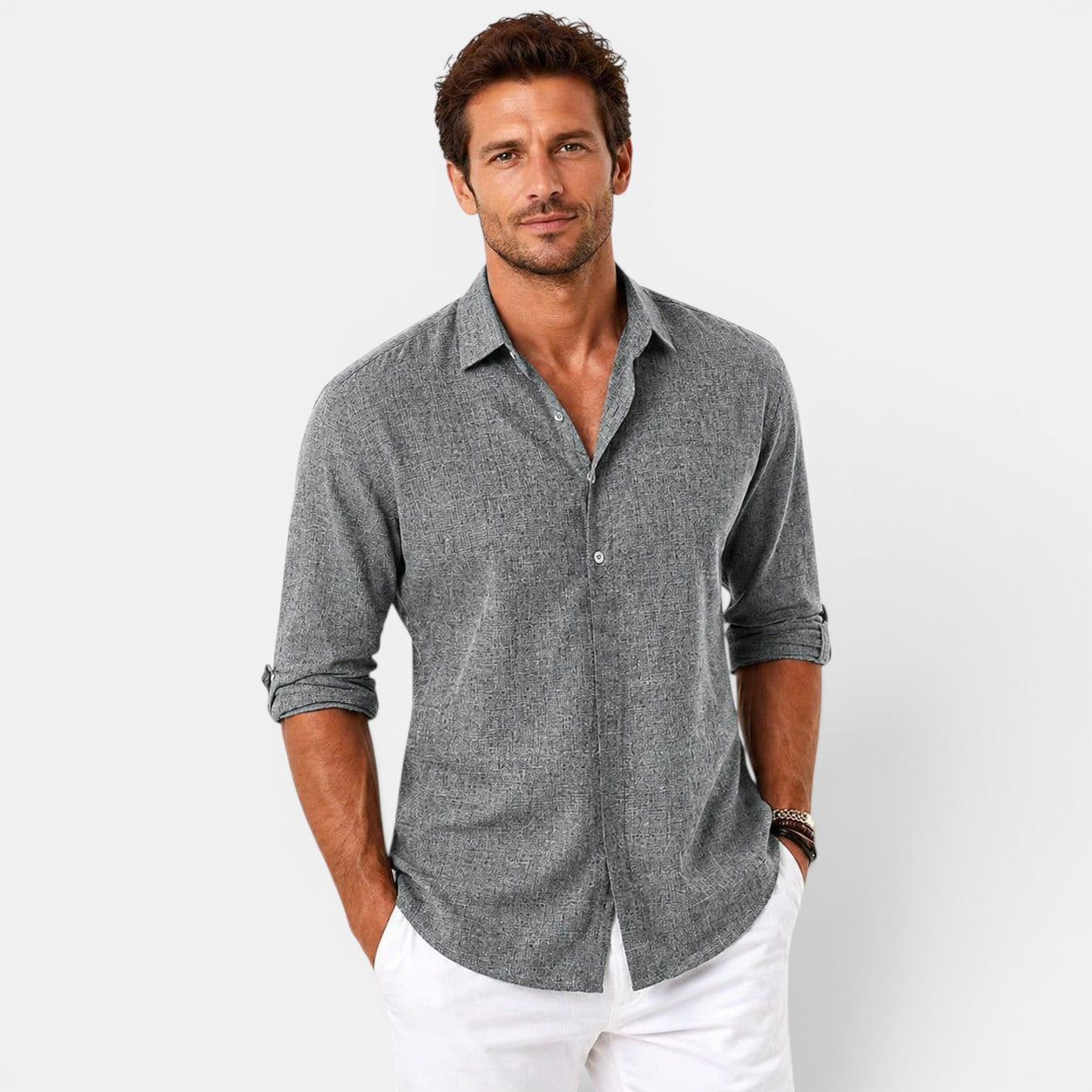 Man wearing a gray button-up shirt and white pants on a light gray background