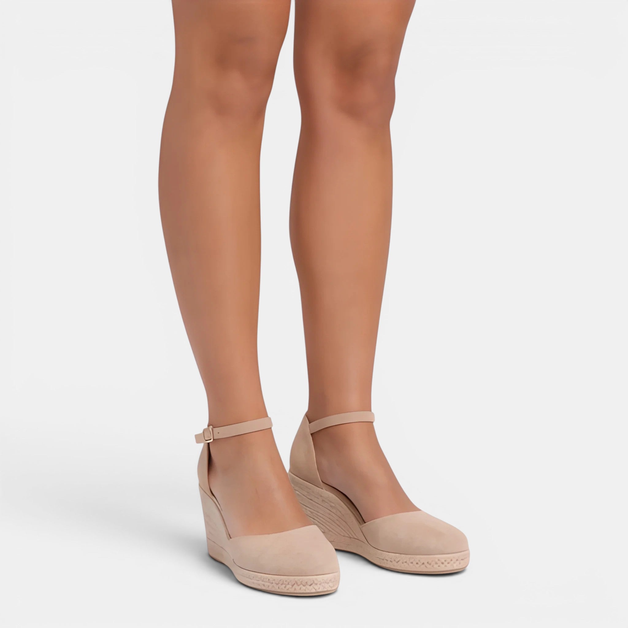 Beige wedge sandals worn with sheer beige tights on a white background