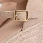 Close-up of a beige sandal with a gold buckle on a blurred background