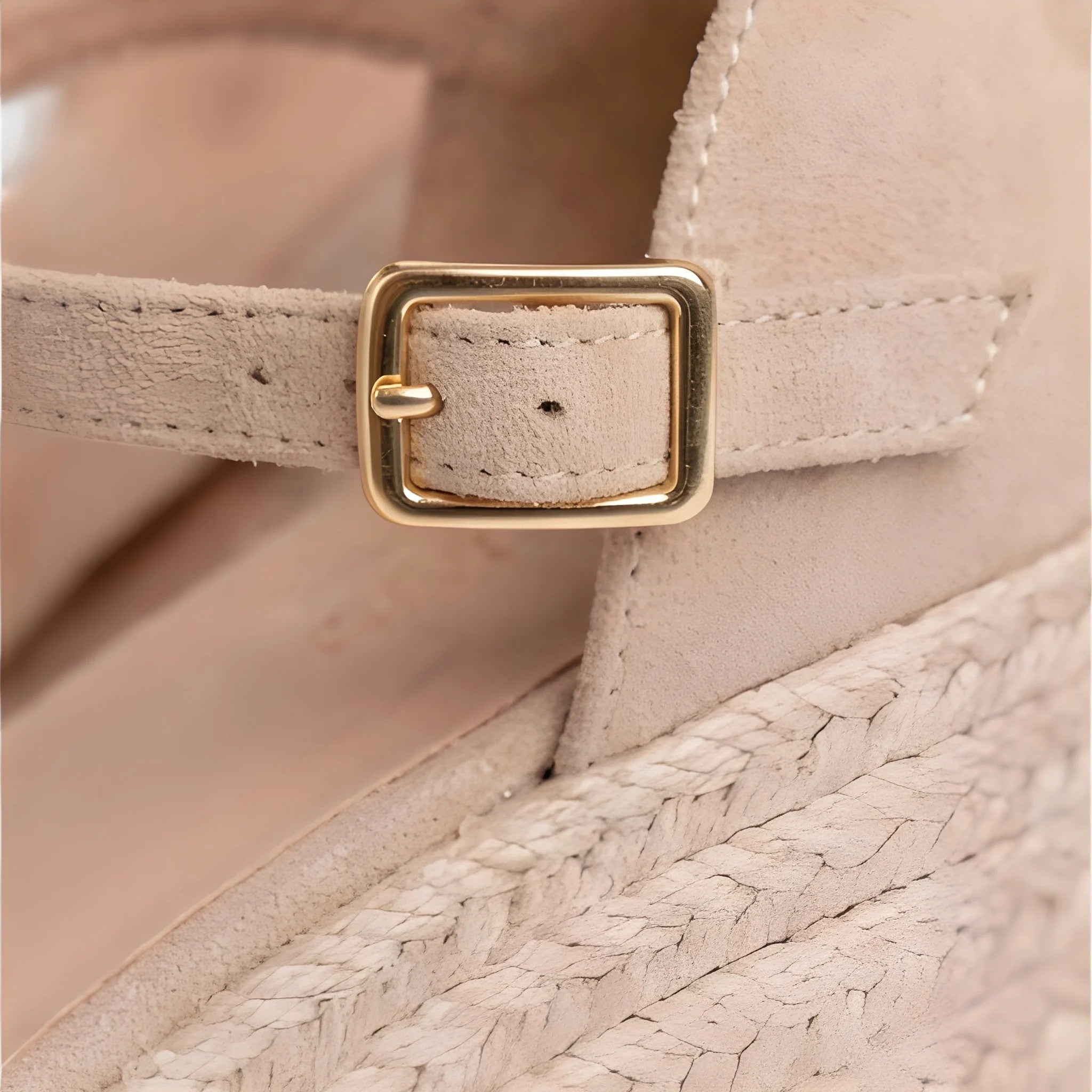 Close-up of a beige sandal with a gold buckle on a blurred background