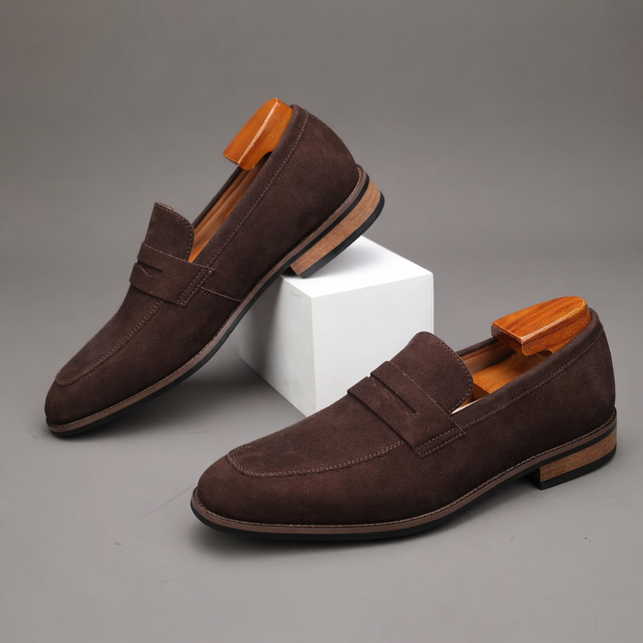 Pair of brown loafers with wooden accents on a gray background