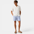 Man wearing a white shirt and blue striped shorts on a white background
