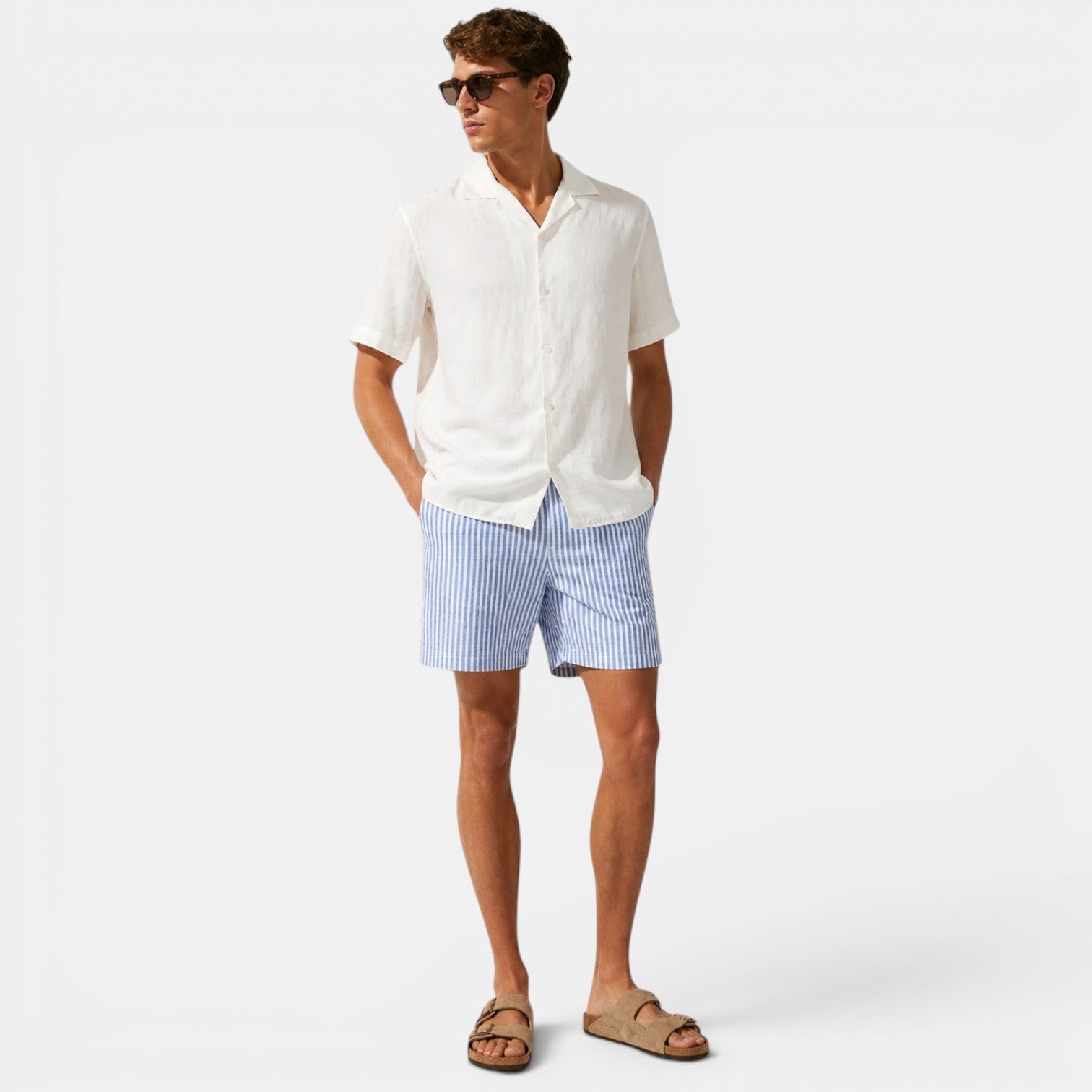 Man wearing a white shirt and blue striped shorts on a white background