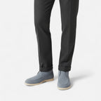 Gray suede shoes worn with black pants on a white background