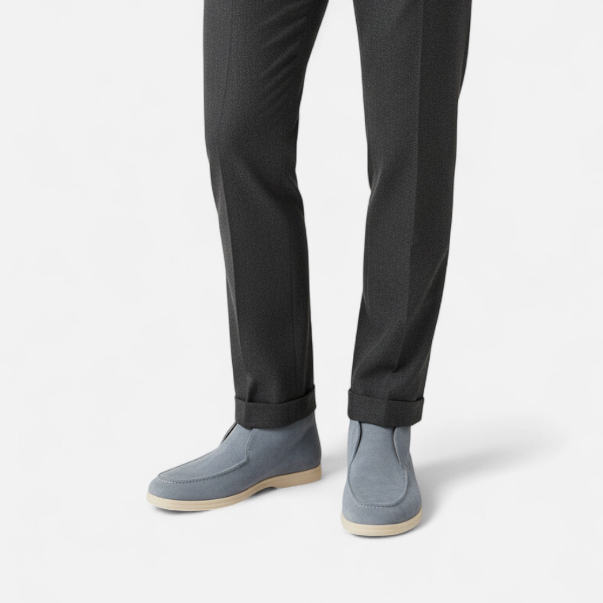 Gray suede shoes worn with black pants on a white background