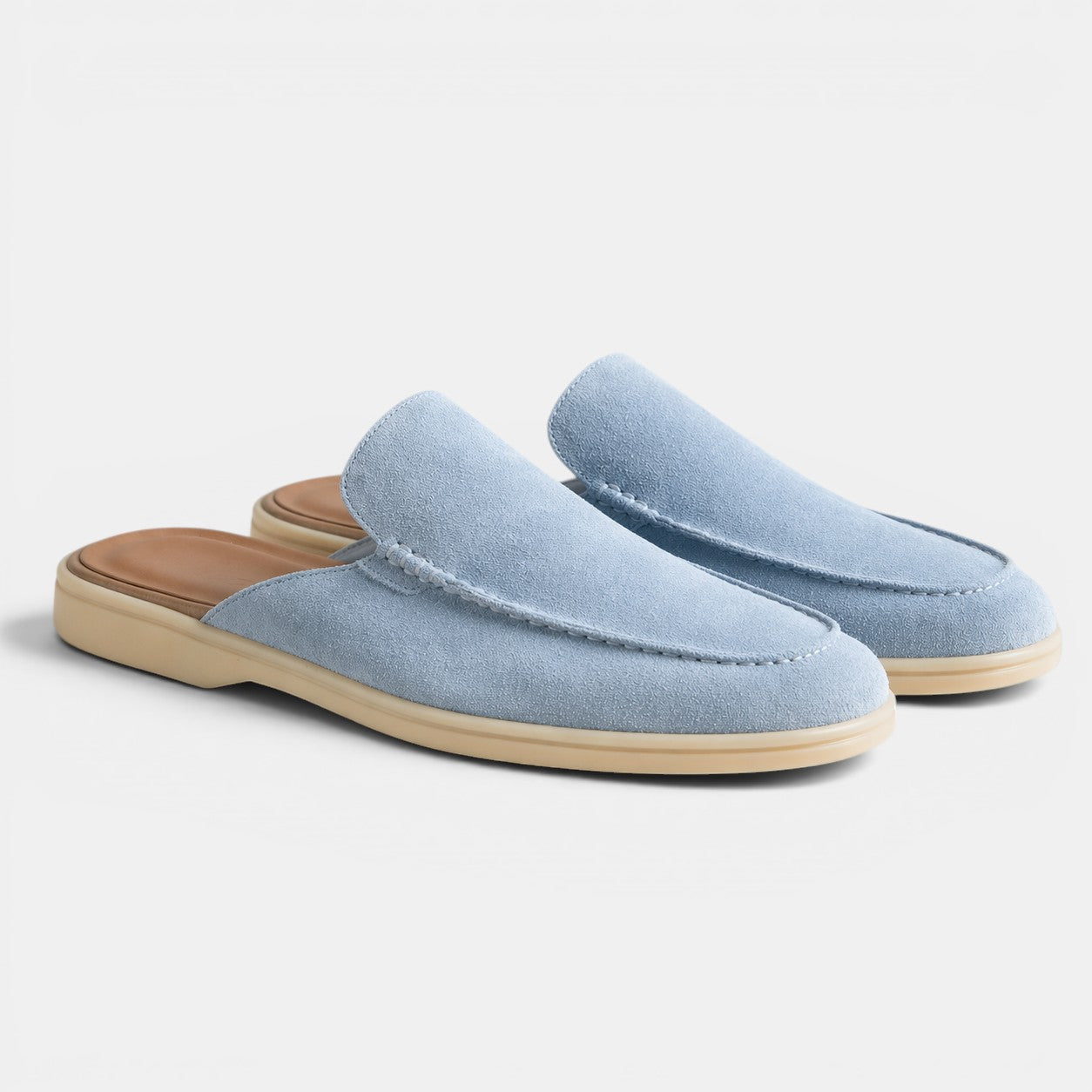 Pair of light blue slippers with a brown sole on a white background