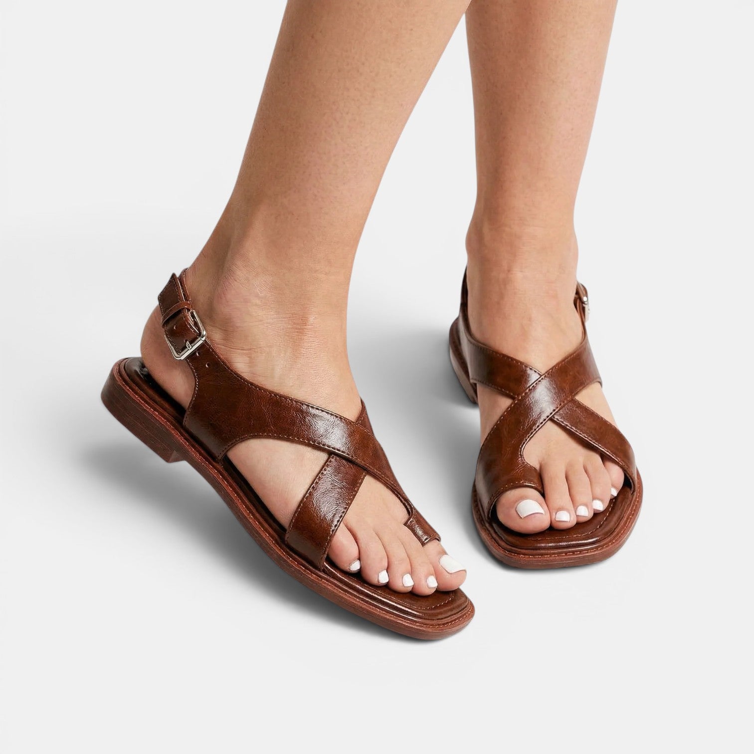 Brown sandals worn by a person on a light gray background