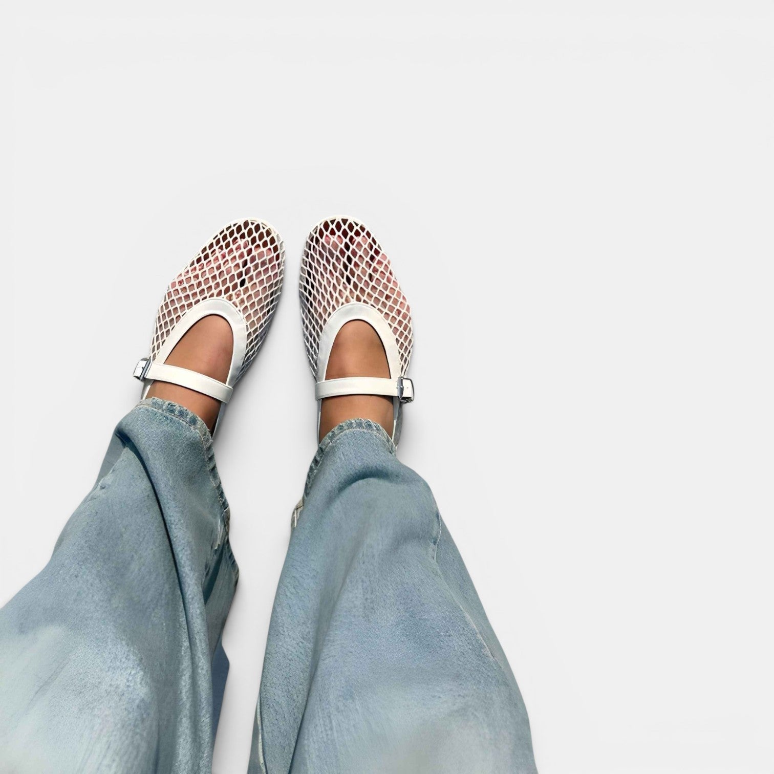 Mesh sandals with white straps worn with light blue jeans on a white background