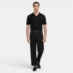 Man wearing a black polo shirt and black pants on a white background